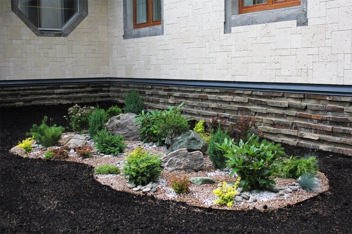 parterre de fleurs avec des rochers près de la maison