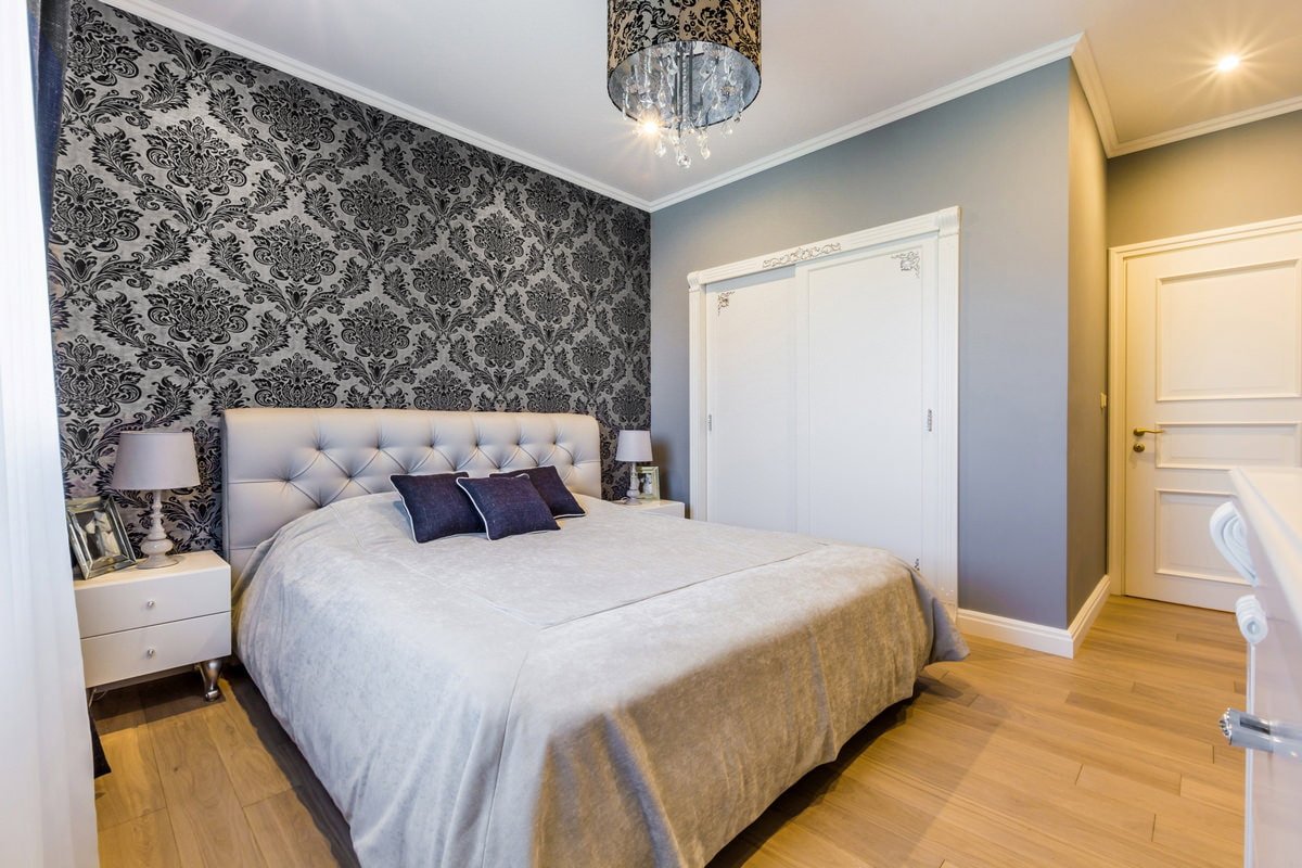 Papier peint gris avec un motif monogramme foncé dans la chambre