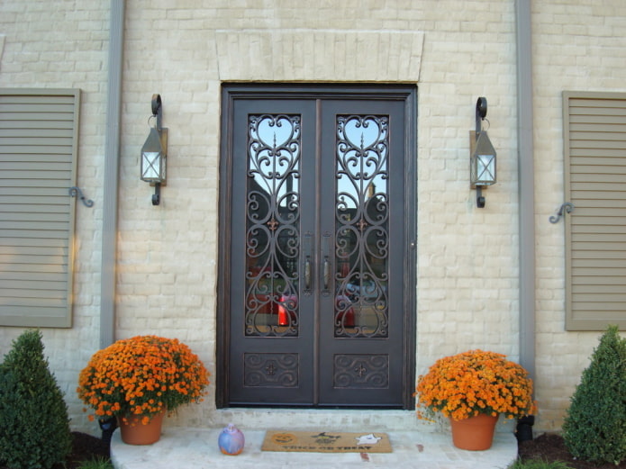porche d'une maison de campagne avec porte d'entrée en fer forgé et verre