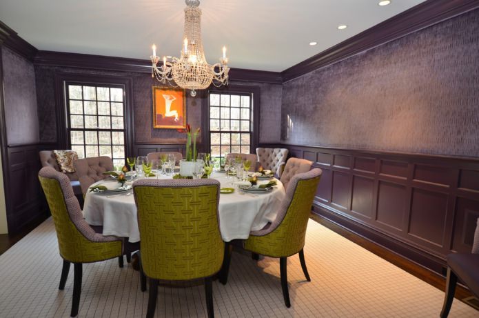 salle à manger avec papier peint violet foncé et chaises vertes et lilas