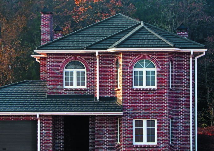 une maison en brique rouge foncé avec un toit noir