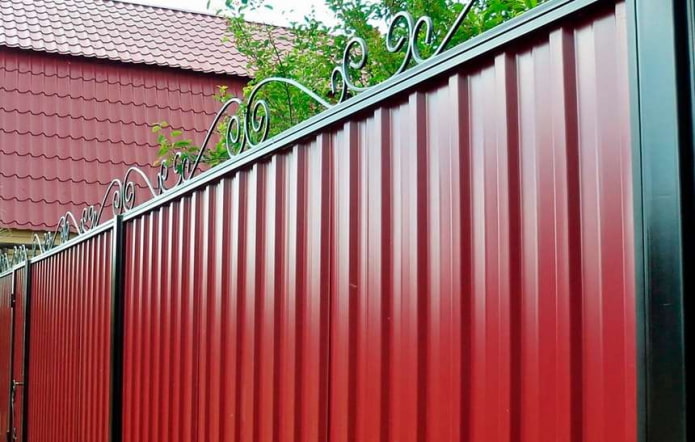 Clôture rouge en tôle profilée avec éléments forgés