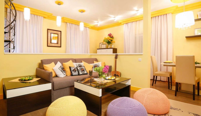 Salon jaune clair avec coussins multicolores et poufs tricotés